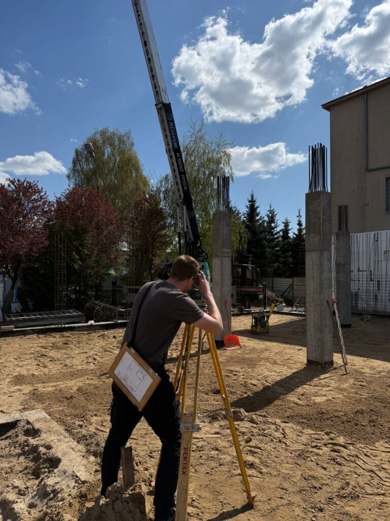 Geodeta wykonuje pomiar tachimetrem na budowie
